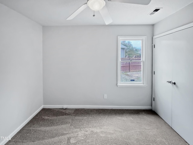 carpeted empty room with a ceiling fan, visible vents, and baseboards