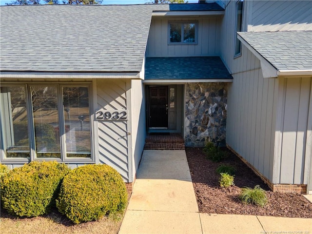 entrance to property featuring board and batten siding and roof with shingles