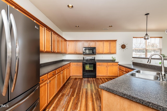 kitchen with dark countertops, recessed lighting, dark wood-style floors, black appliances, and a sink