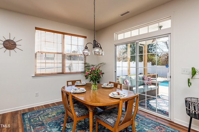 dining room featuring wood finished floors, visible vents, a chandelier, and baseboards