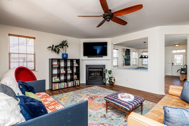 living area featuring visible vents, wood finished floors, a fireplace, baseboards, and ceiling fan