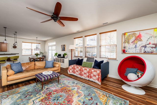 living area with a ceiling fan, wood finished floors, visible vents, and baseboards