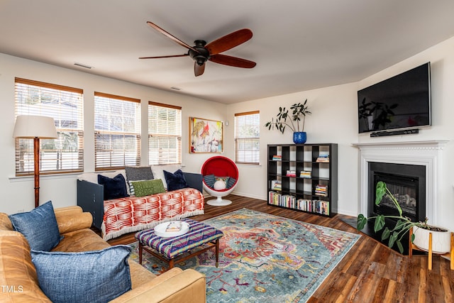 living area featuring a glass covered fireplace, wood finished floors, visible vents, and a wealth of natural light