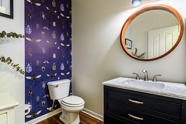 full bathroom featuring toilet, vanity, baseboards, and wood finished floors