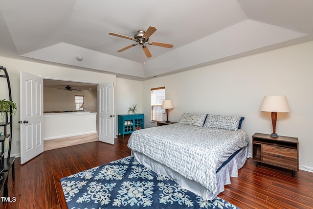 bedroom with a raised ceiling, wood finished floors, baseboards, and lofted ceiling