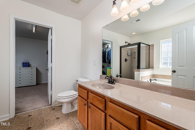 full bath with visible vents, a walk in closet, toilet, a stall shower, and vanity