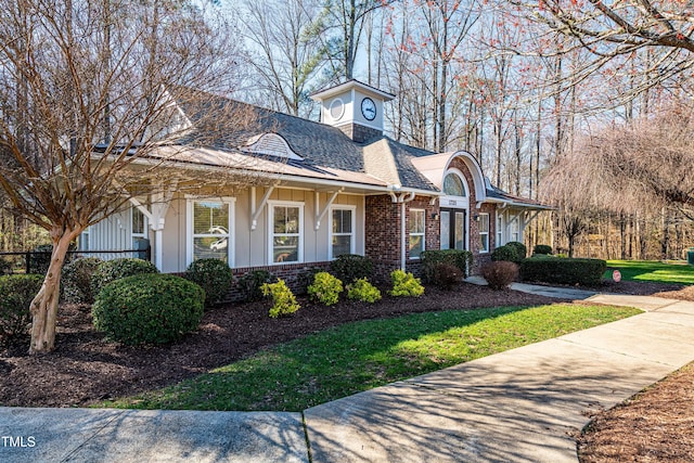 view of front of property with board and batten siding, a front lawn, and brick siding