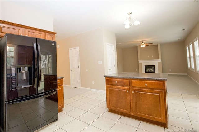 440 Moss Pink Dr, Vass, NC 28394 - kitchen featuring light tile patterned flooring, brown cabinets, black fridge, ceiling fan with notable chandelier, and a glass covered fireplace