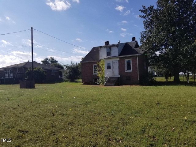 exterior space featuring brick siding, a chimney, and a front lawn