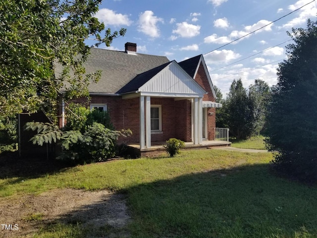 view of home's exterior featuring a lawn, a chimney, brick siding, and a shingled roof