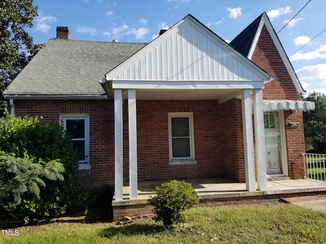 back of property featuring brick siding, roof with shingles, and a chimney