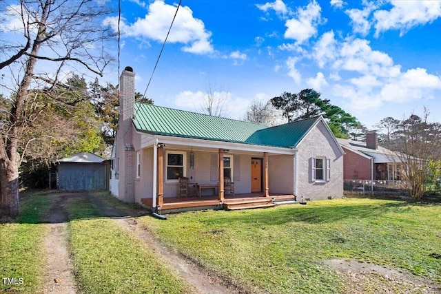 view of front of property featuring driveway, a front lawn, covered porch, brick siding, and a chimney