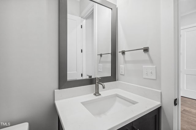 bathroom with toilet, vanity, and wood finished floors