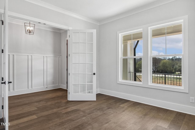 unfurnished bedroom with crown molding, baseboards, dark wood finished floors, a wainscoted wall, and a decorative wall