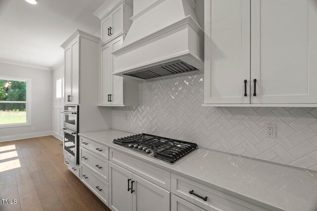 9004 Penny Rd, Raleigh, NC 27606 - kitchen featuring premium range hood, appliances with stainless steel finishes, light countertops, white cabinets, and backsplash