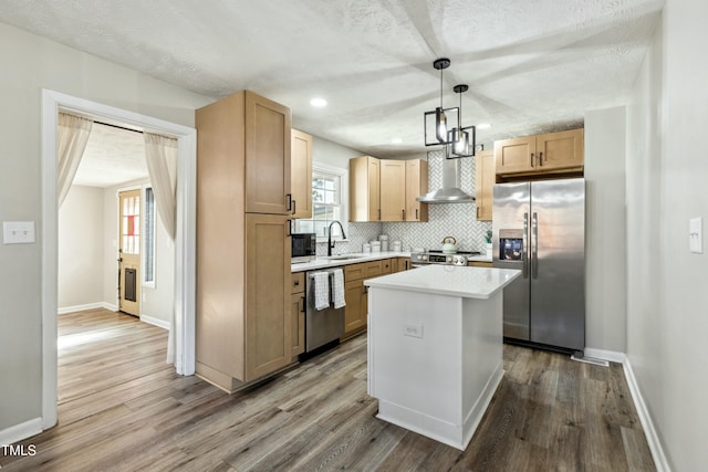 kitchen with a sink, stainless steel appliances, light countertops, wall chimney range hood, and backsplash