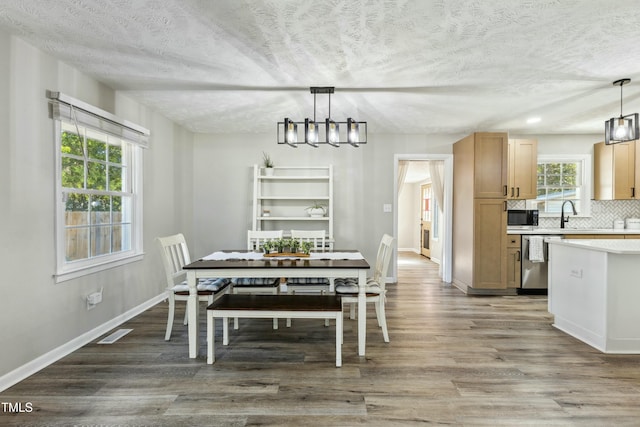 dining space featuring visible vents, a textured ceiling, baseboards, and wood finished floors