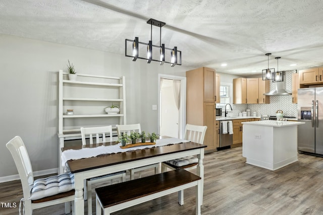 kitchen with stainless steel appliances, decorative backsplash, light countertops, wall chimney range hood, and light wood-type flooring