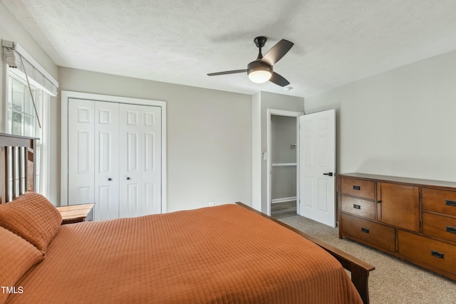 carpeted bedroom featuring ceiling fan, a closet, and a textured ceiling