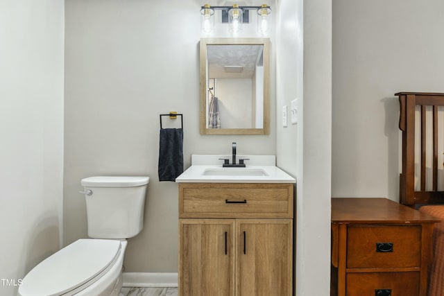 bathroom with baseboards, toilet, and vanity