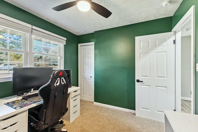 office featuring ceiling fan, light carpet, baseboards, and a textured ceiling