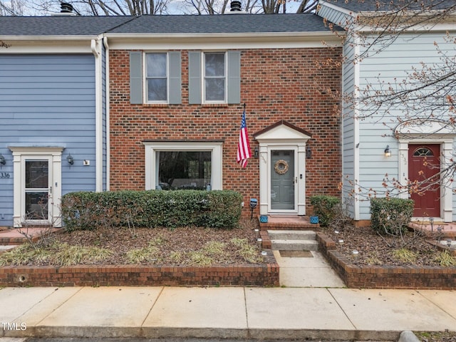 townhome / multi-family property with brick siding and a shingled roof