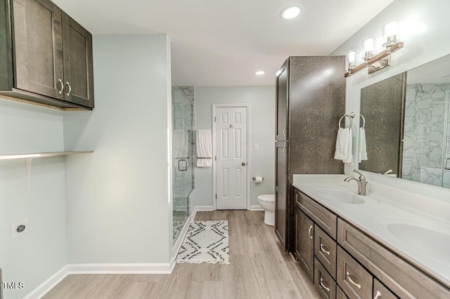 bathroom featuring a shower stall, toilet, wood finished floors, and a sink