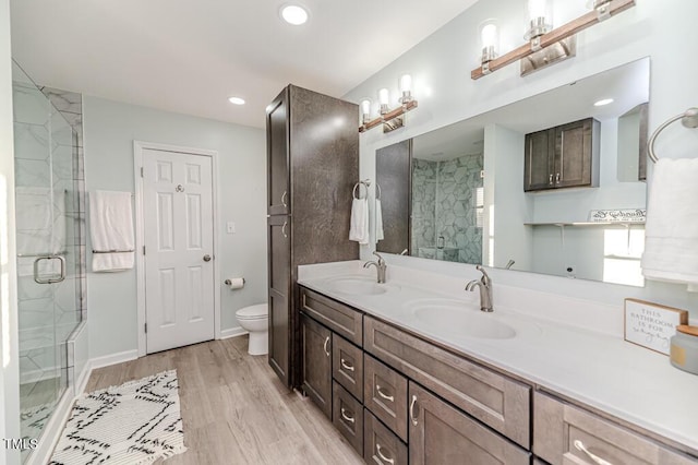 full bath with double vanity, wood finished floors, a stall shower, and a sink