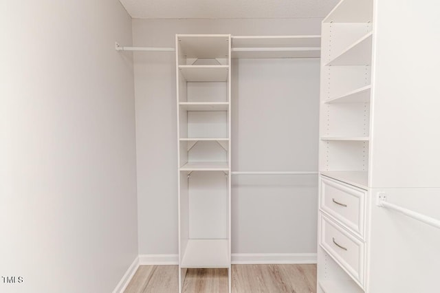 walk in closet with light wood-style floors