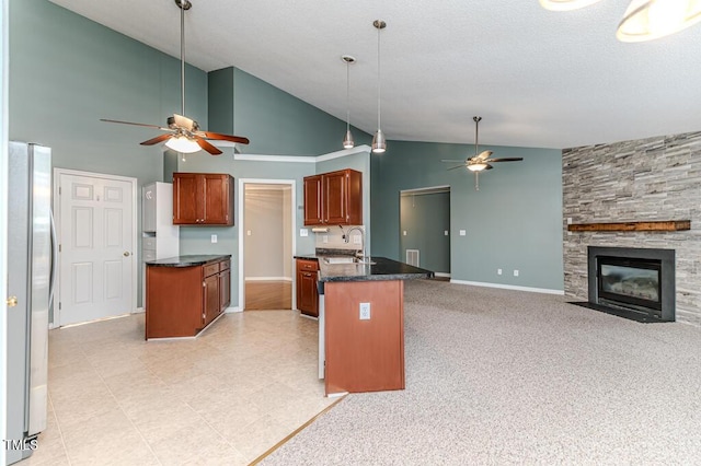 kitchen featuring open floor plan, a peninsula, a fireplace, freestanding refrigerator, and a ceiling fan