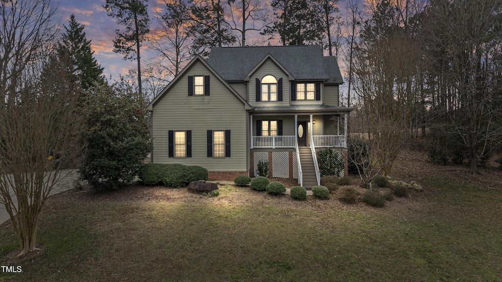 traditional home featuring stairs, a porch, a yard, and roof with shingles