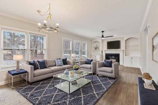 living room with a glass covered fireplace, a healthy amount of sunlight, wood finished floors, and crown molding