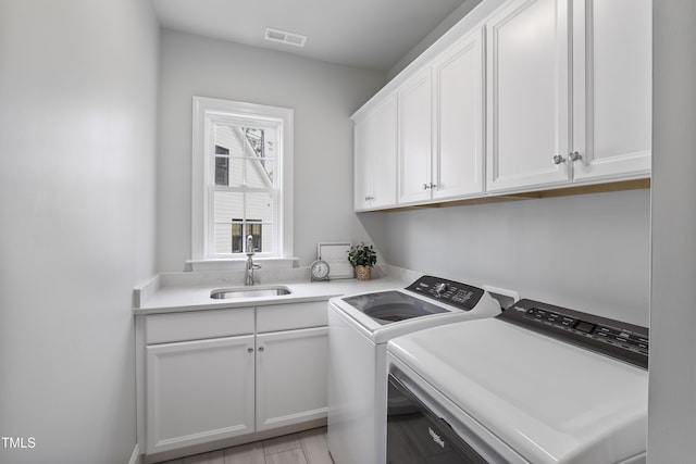 washroom featuring cabinet space, separate washer and dryer, visible vents, and a sink