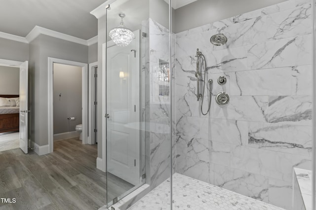 ensuite bathroom featuring a marble finish shower, crown molding, baseboards, toilet, and wood finished floors