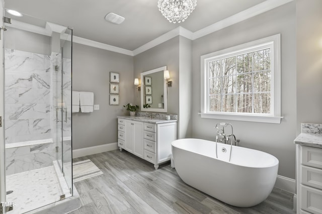 bathroom featuring vanity, baseboards, a marble finish shower, a freestanding tub, and crown molding