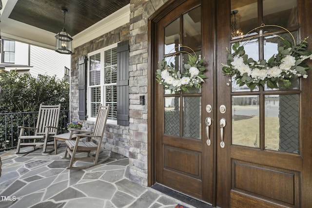 property entrance featuring french doors, stone siding, and a porch