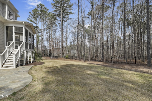 view of yard featuring stairway, a fenced backyard, and a sunroom