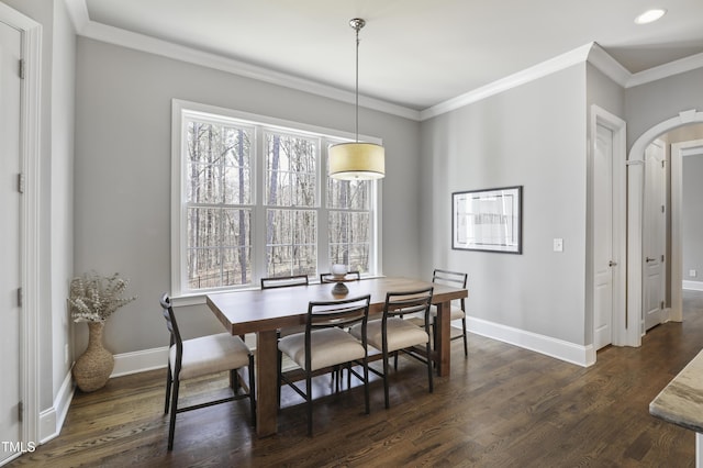 dining room featuring dark wood finished floors, arched walkways, crown molding, and baseboards