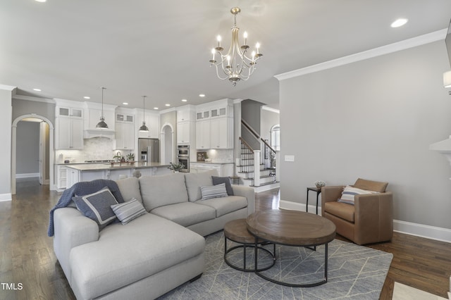 living area featuring arched walkways, a notable chandelier, dark wood finished floors, and crown molding