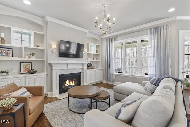 living area featuring a notable chandelier, a fireplace with flush hearth, plenty of natural light, and ornamental molding