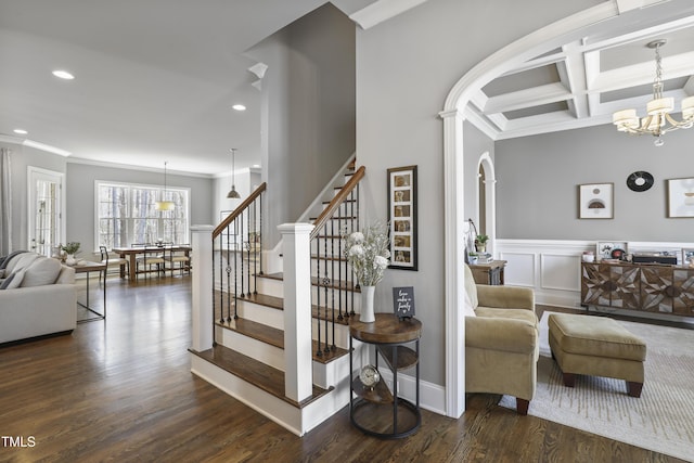 stairway featuring beam ceiling, a notable chandelier, coffered ceiling, wood finished floors, and crown molding