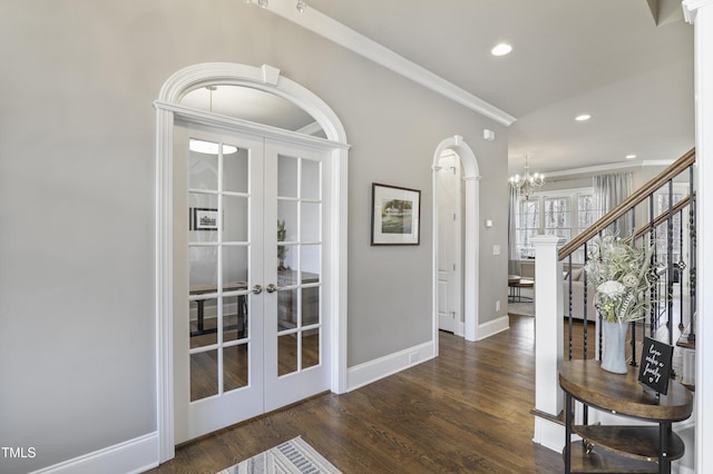 entryway with a notable chandelier, french doors, crown molding, and wood finished floors