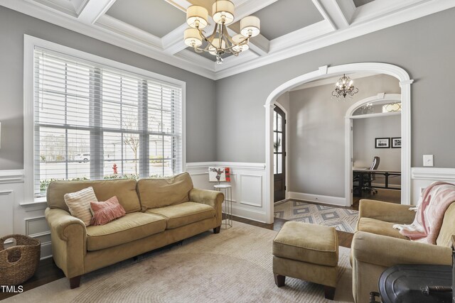 living area featuring beamed ceiling, arched walkways, coffered ceiling, and an inviting chandelier