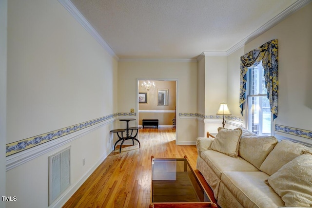 living area featuring crown molding, baseboards, visible vents, and light wood finished floors