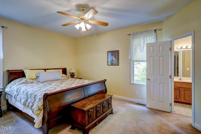 bedroom with visible vents, baseboards, light colored carpet, ensuite bathroom, and a sink