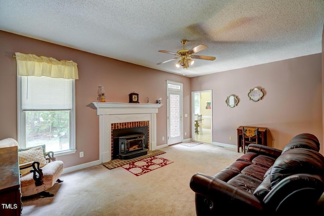 living area featuring baseboards, carpet, ceiling fan, and a textured ceiling