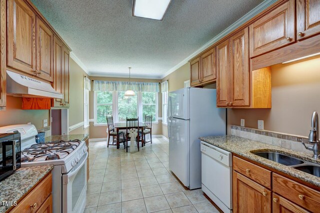 kitchen featuring crown molding, under cabinet range hood, brown cabinetry, white appliances, and a sink