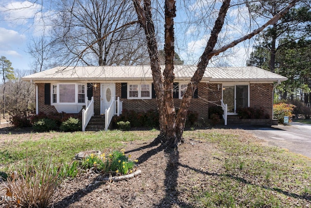 single story home with brick siding and metal roof