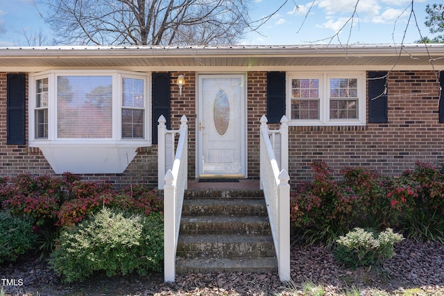 doorway to property featuring brick siding and metal roof