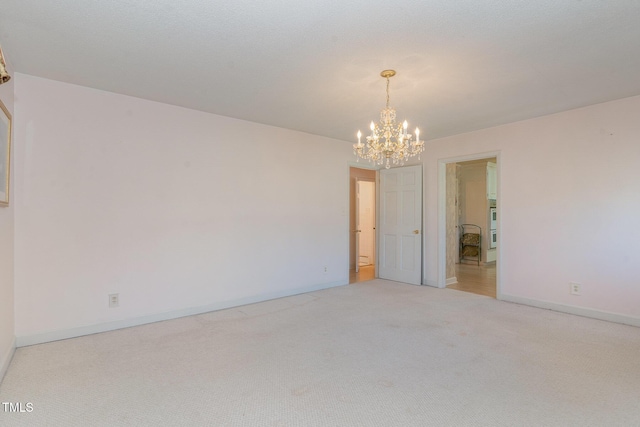 unfurnished room featuring light carpet, a notable chandelier, and baseboards